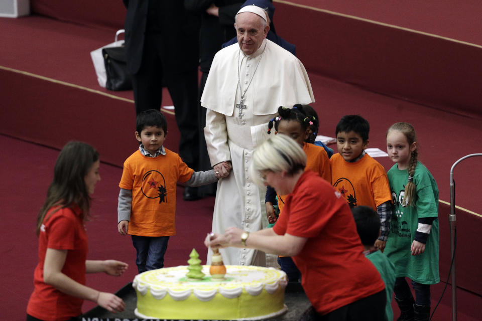 Pope Francis walks with children towards a cake he was offered on the eve of his 82nd birthday during audience with children and family from the dispensary of Santa Marta, a Vatican charity that offers special help to mothers and children in need, in the Paul VI hall at the Vatican, Sunday, Dec. 16, 2018. (AP Photo/Gregorio Borgia)