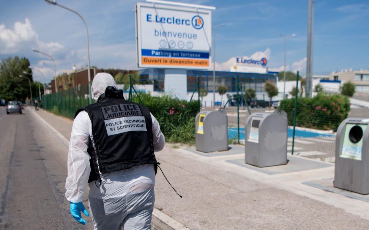 A member of the French Forensic police walk outside the grounds of a supermarket where two people were injured in June - AFP