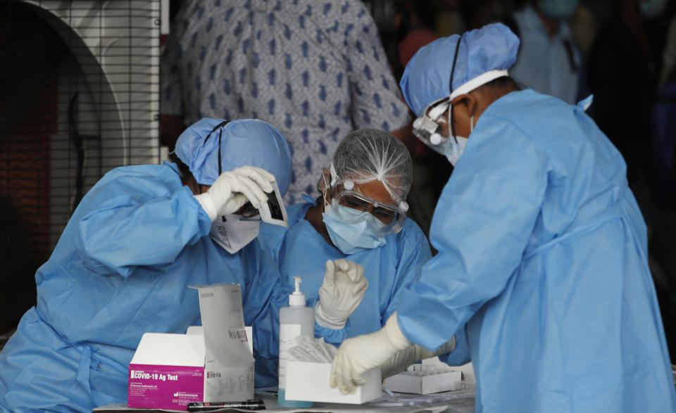 Health workers conduct COVID-19 antigen tests for migrant workers in New Delhi, India, Aug. 18, 2020. In June, India began using the cheaper, faster but less accurate tests to scale up testing for the coronavirus — a strategy that the U.S. is now considering. (AP Photo/Manish Swarup)