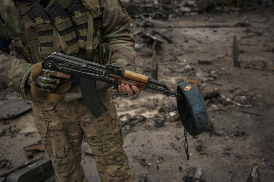 A Ukrainian serviceman with a Russian beret from destroyed Russian military vehicles on his weapon, at the Antonov airport