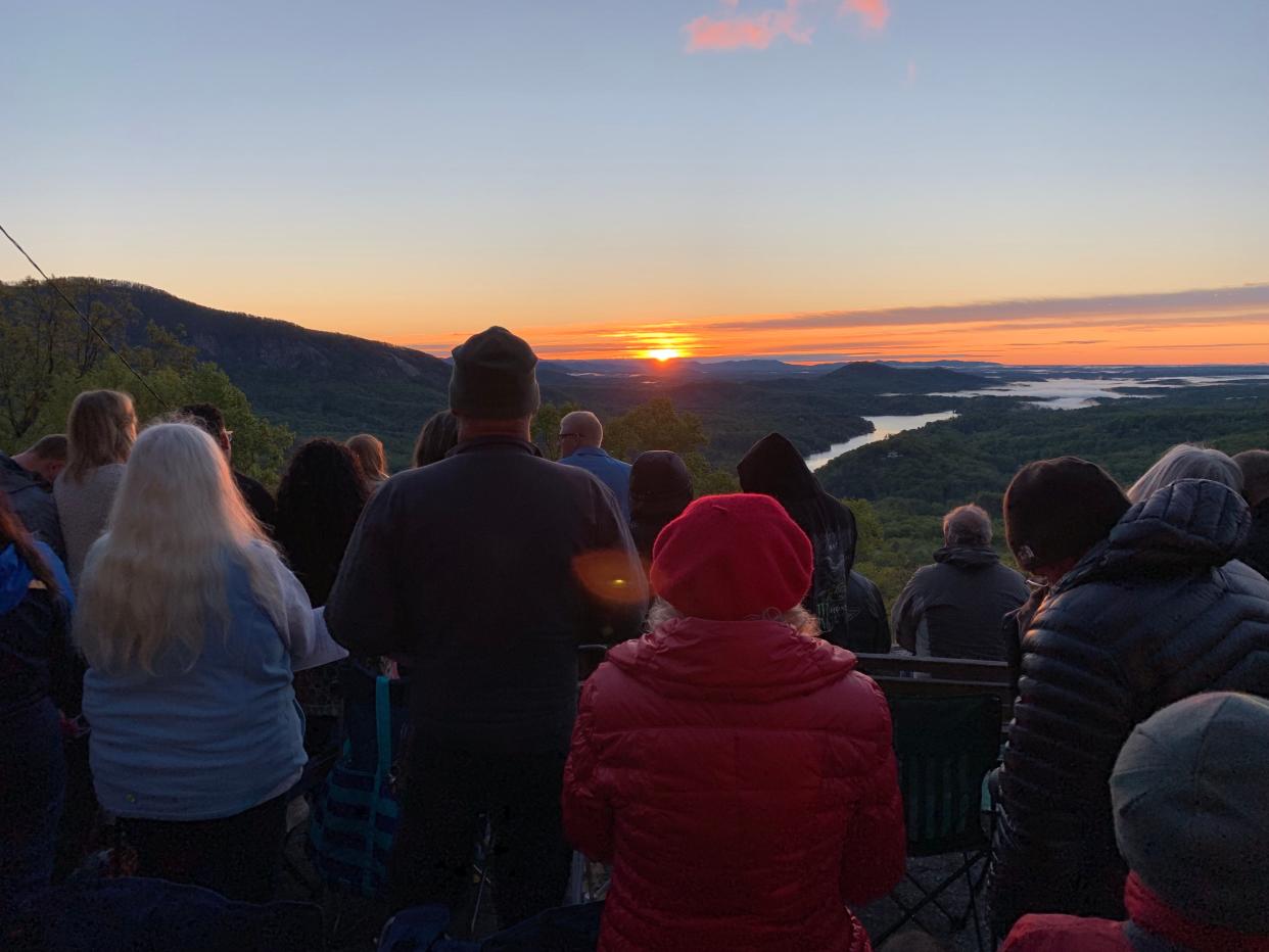 Worshipers watch the sunrise over Lake Lure from Chimney Rock Park's Easter sunrise service on April 21, 2019.