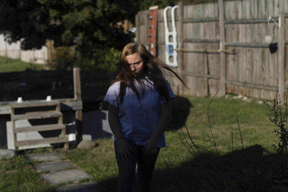 Olivia walks through the backyard of her home in Columbus, Ohio, Tuesday, Oct. 24, 2023, where she lives with her grandfather Joe Smith. Smith did not picture raising Olivia, but when his daughter's substance use disorder meant she couldn't care for her child, that's where he and his late wife found themselves nineteen years ago. (AP Photo/Carolyn Kaster)