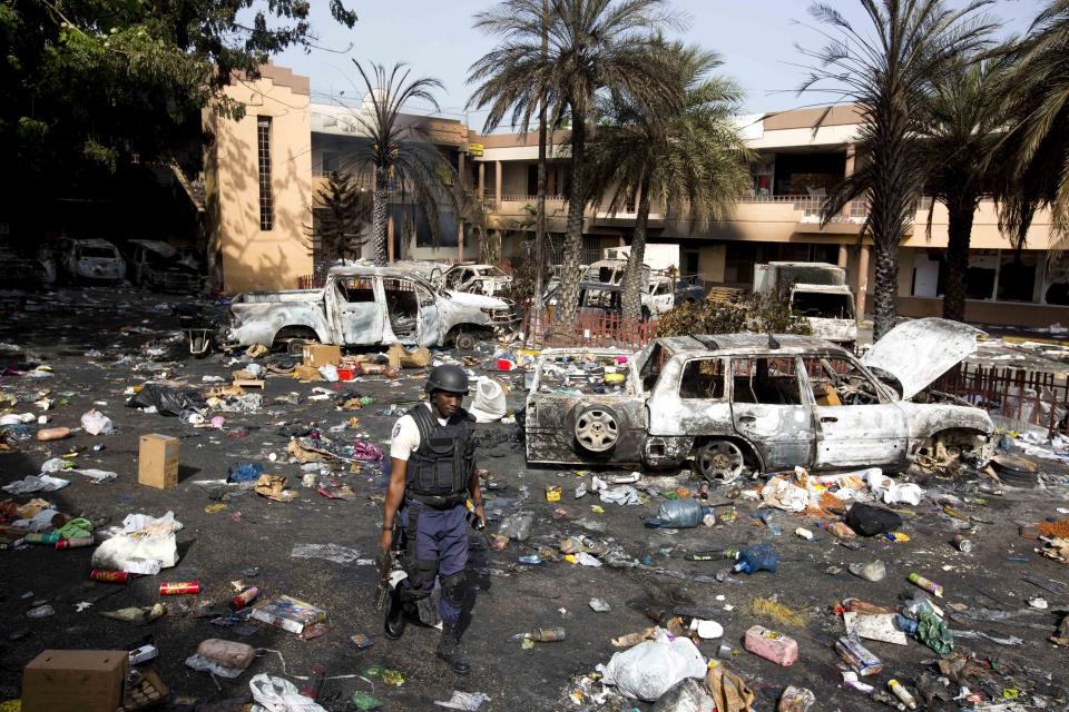 <p>A police officer walks through the parking lot of the Delimart supermarket complex, where vehicles sit charred and looted merchandise lies scattered after two days of protests against a planned hike in fuel prices in Port-au-Prince, Haiti, Sunday, July 8, 2018. (Photo: Dieu Nalio Chery/AP) </p>