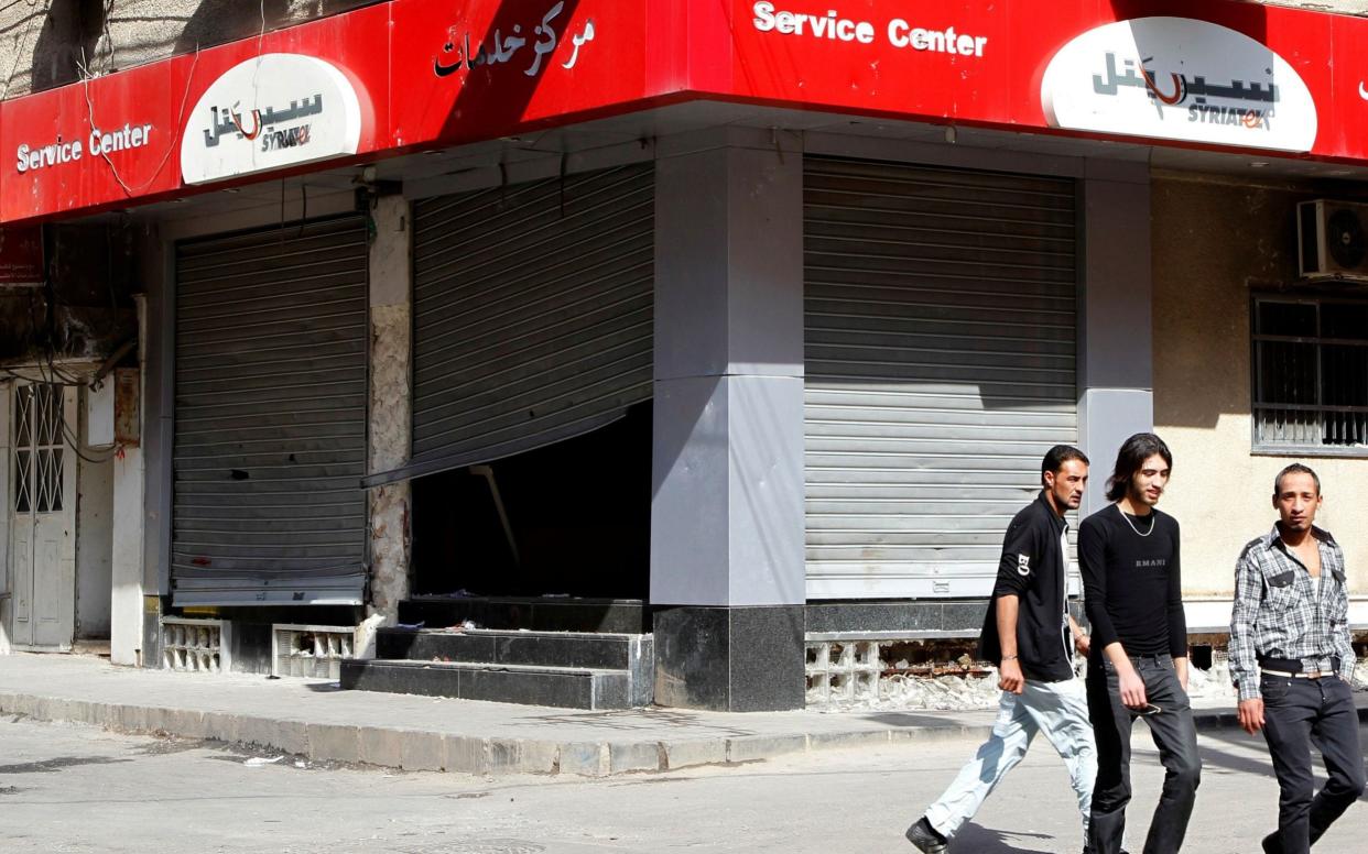 People walk past a Syriatel shop - REUTERS/Khaled al-Hariri