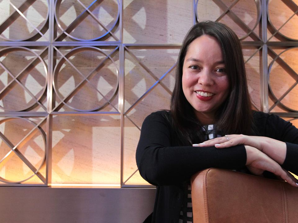 A woman in a black sweater and crossed arms looks at the camera.