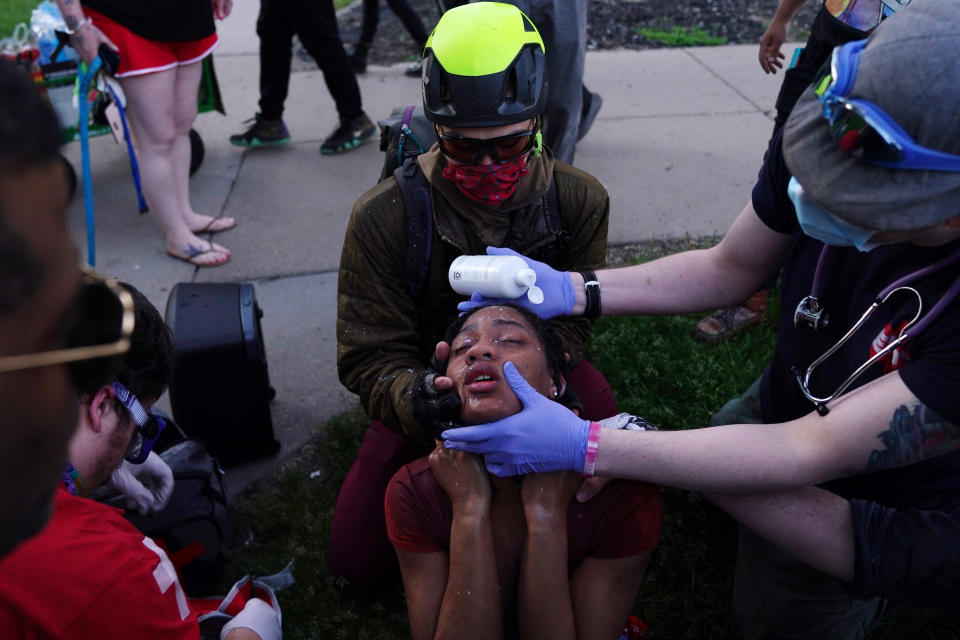 Citizen medics help a protester clear her eyes as police move in with tear gas against protesters near the Minneapolis Police 5th Precinct on May 30. (Photo: Star Tribune via Getty Images via Getty Images)