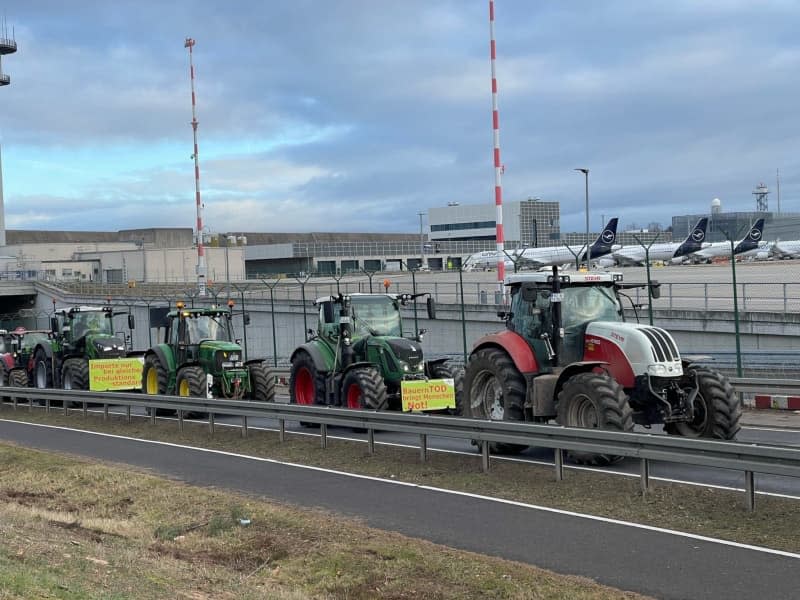 Tractors drive past on a road at Frankfurt Airport. Hundreds of farmers demonstrate against the expiry of tax refunds for agricultural diesel with a protest drive around Germany's busiest airport in Frankfurt. Mike Seeboth/dpa