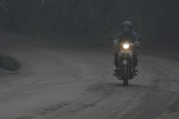 <p>A motorist rides his motorbike during a shower of ash and rain from Mount Agung volcano during an eruption in Bebandem Village, Karangasem, Bali, Indonesia Nov. 26, 2017. (Photo: Antara Foto/Fikri Yusuf/Reuters) </p>