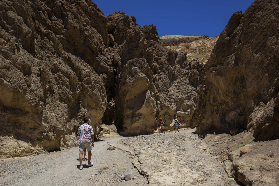 Tourists hike the Golden Canyon trail on July 11, 2023, in Death Valley National Park, Calif. A 71-year-old Los Angeles-area man died at the trailhead on Tuesday, July 18, as temperatures reached 121 degrees (49 Celsius) or higher and rangers suspect heat was a factor, the National Park Service said in a statement Wednesday. (AP Photo/Ty ONeil)