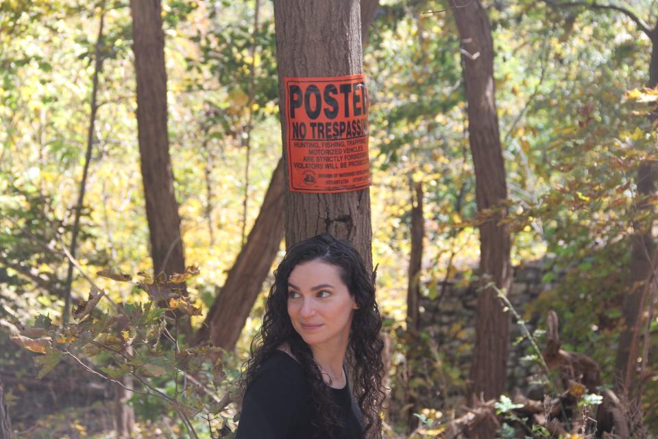 A woman poses in front of a no trespassing sign.