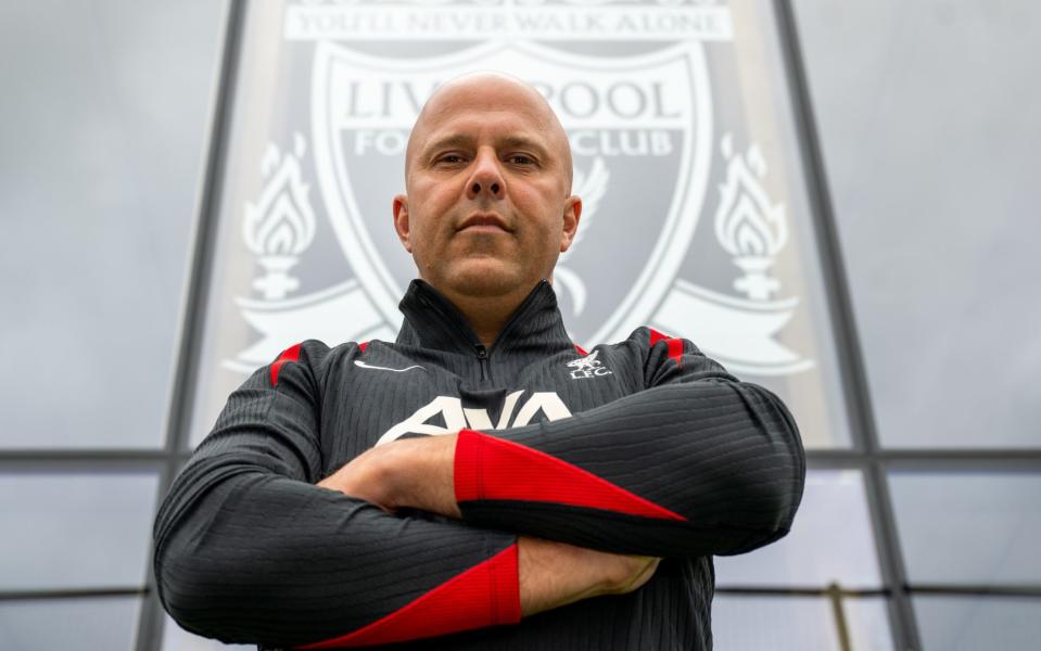 Arne Slot in front of the Liverpool badge on the front of their training base