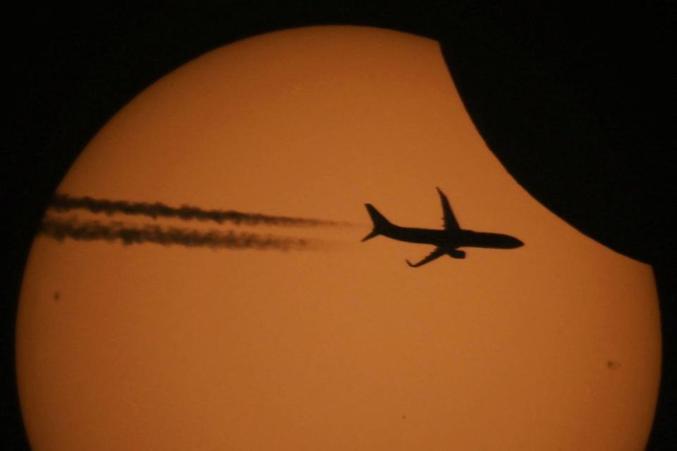 A picture taken through a telescope shows a silhouette of an aircraft against the sun during a partial solar eclipse in the settlement of Kojori outside Tbilisi, Georgia October 25, 2022. REUTERS/Irakli Gedenidze