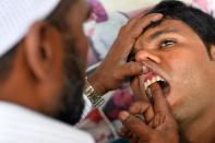 Street dentist Allah Baksh takes measurements for dentures from a customer at his roadside stall at K.R. Market bus stand in Bangalore