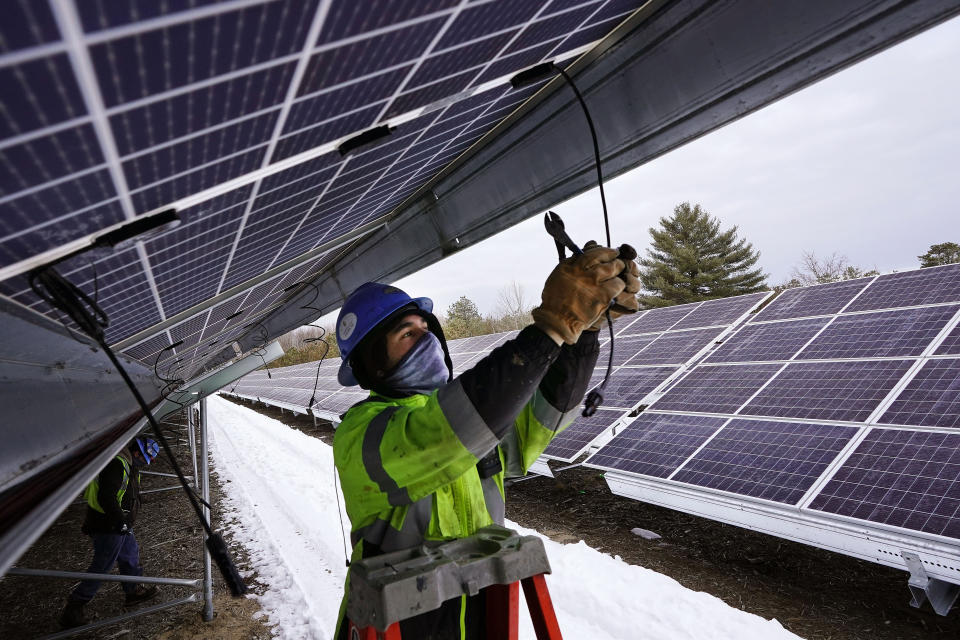 Electrician Zach Newton works on wiring solar panels at the 38-acre BNRG/Dirigo solar farm, Thursday, Jan. 14, 2021, in Oxford, Maine. President Joe Biden wants to change the way the U.S. uses energy by expanding renewables, but faces several challenges. (AP Photo/Robert F. Bukaty)