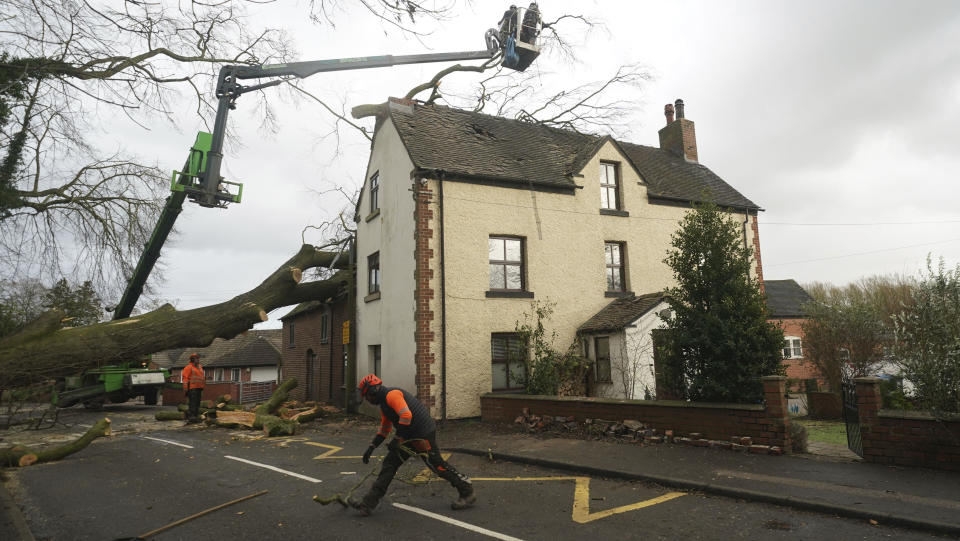 Workmen remove a fallen tree which has damaged the roof of a house in the village of Stanley in Derbyshire, England, Thursday, Dec. 21, 2023. Storm Pia is expected to cause disruption in parts of Scotland, the north of England and Northern Ireland. (Jacob King/PA via AP)