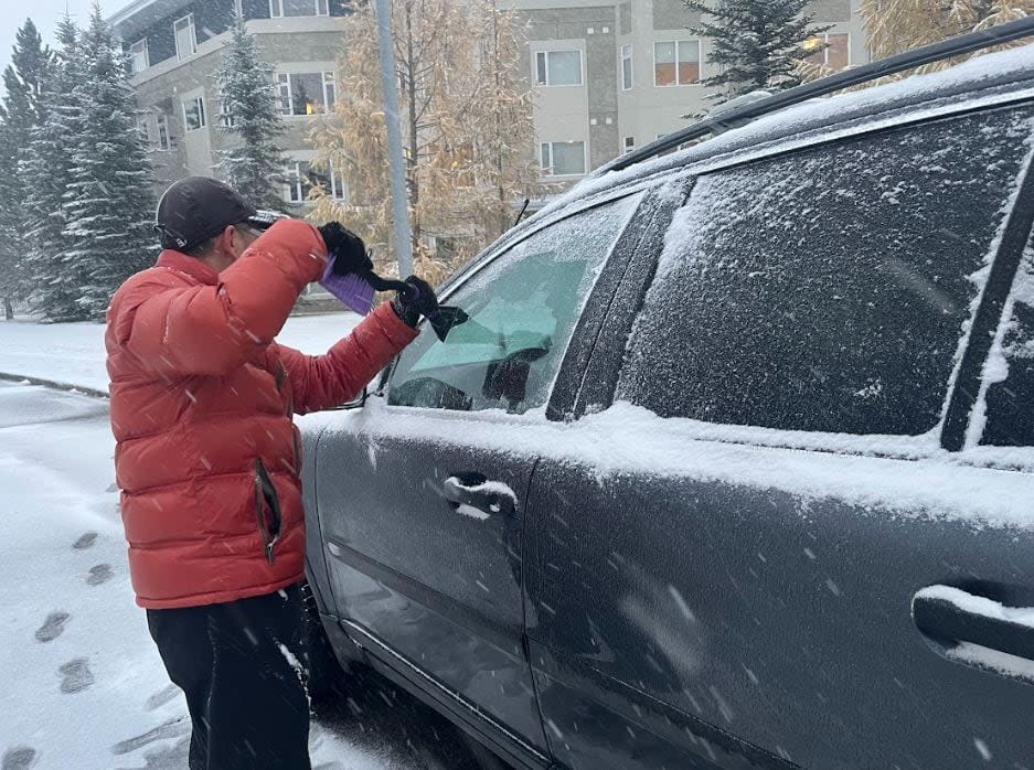 A Calgarian scrapes their car on Monday afternoon. 