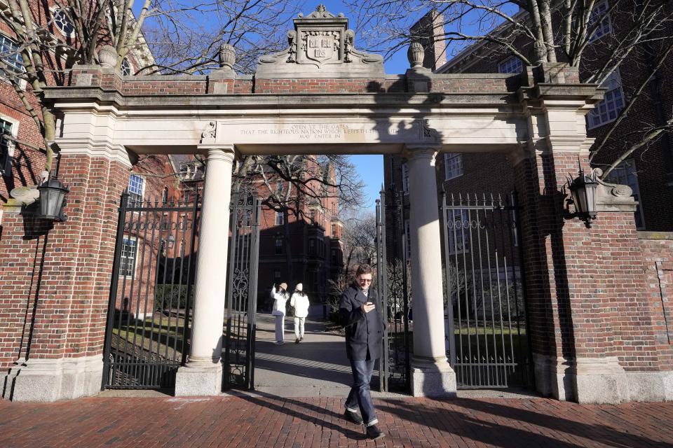 A passer-by walks through a gate to the Harvard University campus, Tuesday, Jan. 2, 2024, in Cambridge, Mass. Harvard University President Claudine Gay resigned Tuesday amid plagiarism accusations and criticism over testimony at a congressional hearing where she was unable to say unequivocally that calls on campus for the genocide of Jews would violate the school's conduct policy. (AP Photo/Steven Senne)