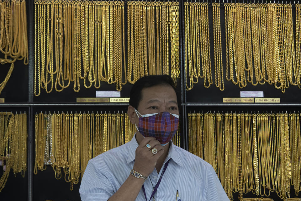 FILE - In this April 16, 2020, file photo, a Thai shopkeeper adjusts his face mask at a gold shop in Bangkok, Thailand. The price of gold surged more than $30 on Monday, July 27, 2020 to over $1,926 per ounce as investors step up buying of the precious metal often sought in times of uncertainty. Gold was trading at $1,926.20 by early afternoon in Asia, up 1.5%, after surging over the weekend. (AP Photo/Sakchai Lalit, File)