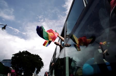 Revellers wave a rainbow flag from a bus during the annual Gay Pride parade along Central Avenue, in San Jose