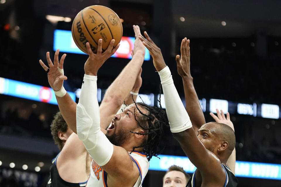 New York Knicks' Jalen Brunson, middle, is fouled as he shoots between Milwaukee Bucks' Khris Middleton, right, and Brook Lopez, left, during the first half of an NBA basketball game Sunday, April 7, 2024, in Milwaukee. (AP Photo/Aaron Gash)