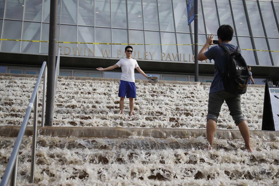 A man poses for a photo on stairs to a parking structure outside UCLA's Pauley Pavilion sporting arena as water flows down from a broken thirty inch water main that was gushing water onto Sunset Boulevard near the UCLA campus in the Westwood section of Los Angeles July 29, 2014. The geyser from the 100-year old water main flooded parts of the campus and stranded motorists on surrounding streets. REUTERS/Danny Moloshok