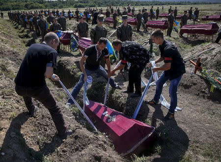 Workers take part in a mass funeral ceremony to bury 57 unidentified members of Ukrainian military forces who were killed in the conflict in eastern regions, in the settlement of Kushuhum near Zaporizhia, Ukraine, August 7, 2015. REUTERS/Gleb Garanich