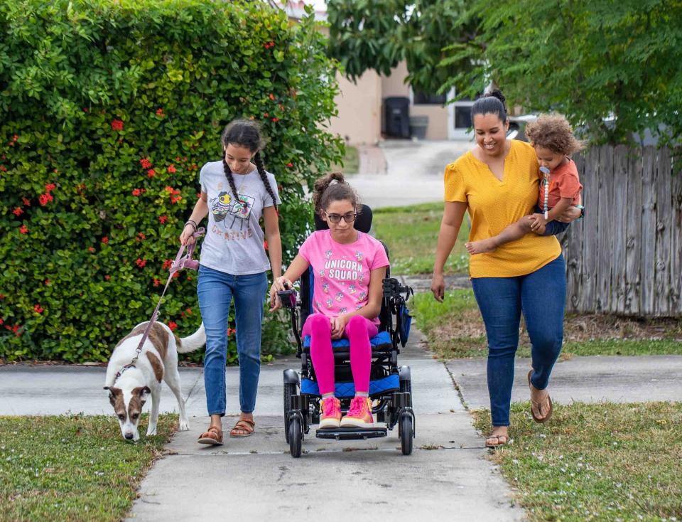 Sakura takes her motorized wheelchair out for a spin with her dog Payton, twin sister Akira, mom Charisma and 2-year-old brother Ezequias.