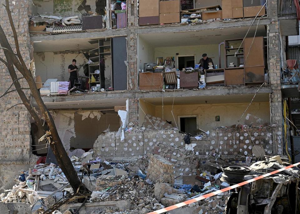 Anwohner sammeln Überreste ihrer zerstörten Wohnungen in einem fünfstöckigen Wohnhaus ein. 