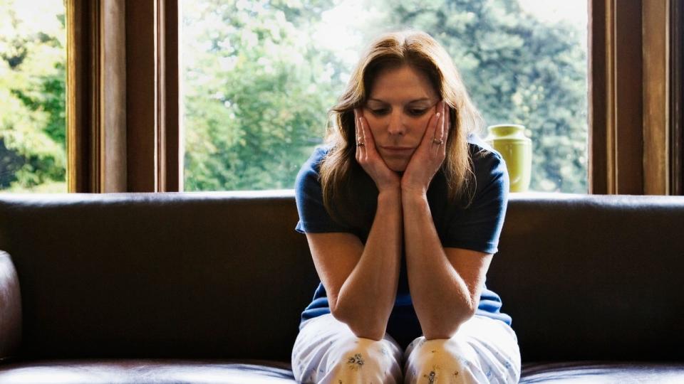 Woman sitting on couch with head in hands