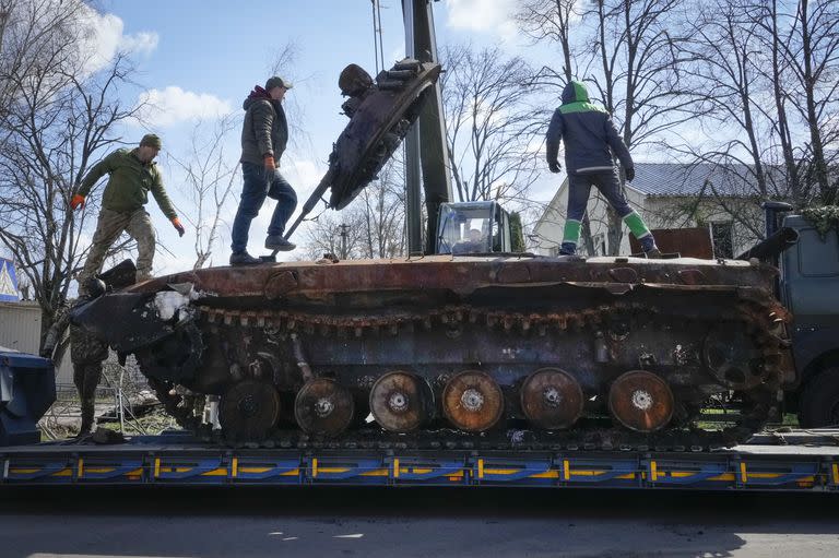 Trabajadores de la carretera cargan un tanque ruso destruido en una plataforma en el pueblo de Andriyivka, cerca de Kyiv, Ucrania, el lunes 11 de abril de 2022.