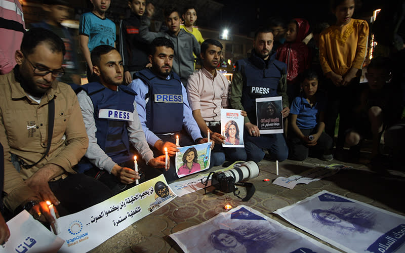 Journalists wearing press vests gathered alongside others to take part in a candlelight vigil for journalist Shireen Abu Akleh