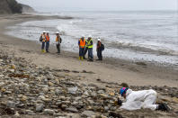 FILE - Shoreline Cleanup Assessment Technique team members, left, evaluate oil coverage as a hand crew worker scraps areas affected by an oil spill at Refugio State Beach, north of Goleta, Calif., on Wednesday, June 10, 2015. A proposal to replace a pipeline near Santa Barbara that was shut down in 2015 after causing California's worst coastal oil spill in 25 years is inching through a government review, even as the state moves toward banning gas-powered vehicles and oil drilling. (AP Photo/Damian Dovarganes, File)