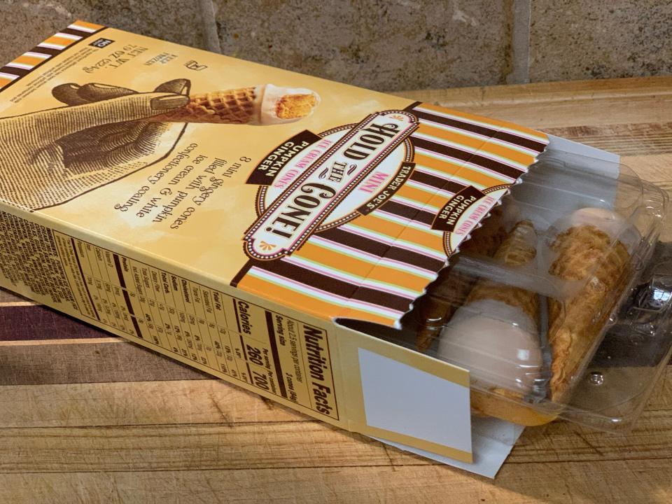 Open box of Trader Joe's pumpkin hold the cone ice cream on a wooden table