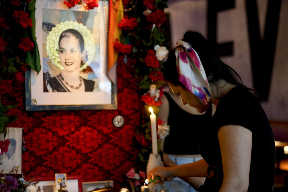 A waitress lights a candle on an altar dedicated to Argentine former first lady María Eva Duarte de Perón, better known as Eva Perón, or Evita, at the Santa Evita restaurant in the Palermo neighborhood of Buenos Aires, Argentina, Sunday, Jan. 28, 2024. (AP Photo/Natacha Pisarenko)