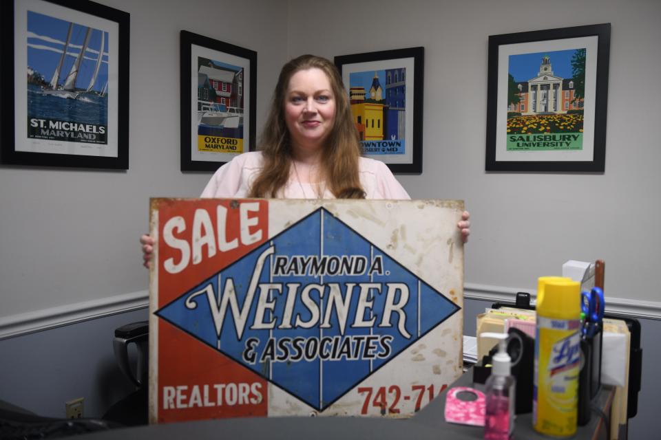 Libby, daughter of owner Michael Weisner, poses with an original sign from Weisner Real Estate, started in 1938, in Salisbury, Maryland, on June 23, 2020.