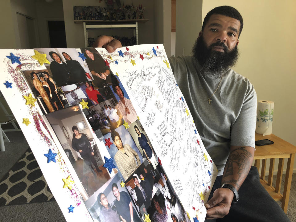 Roland Mack holds a poster with pictures and messages made by family members in memory of his sister, Chantee Mack, in District Heights, Md., on Friday, June 19, 2020. The Prince George's County, Md., public health worker died of COVID-19 after, family and co-workers believe, she and several colleagues contracted the disease in their office. “She was a good soul — strong,” said her brother. “It’s so messed up.” (AP Photo/Federica Narancio)