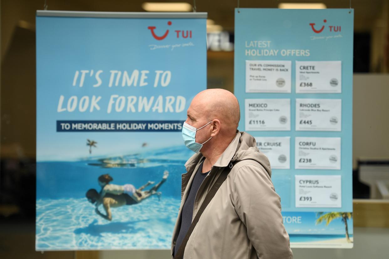 A man wearing a face mask or covering due to the COVID-19 pandemic, walks past the window of a TUI travel agent's holiday shop in Liverpool, north west England on October 2, 2020, following the  announcement of new local restrictions for certain areas in the northwest of the country, due to a resurgence of novel coronavirus cases. - The British government on Thursday extended lockdowns to Liverpool and several other towns in northern England, effectively putting more than a quarter of the country under tighter coronavirus restrictions. Health Secretary Matt Hancock said limits on social gatherings would be extended to the Liverpool City region, which has a population of about 1.5 million. (Photo by Oli SCARFF / AFP) (Photo by OLI SCARFF/AFP via Getty Images)