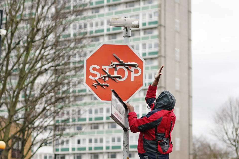 People remove a piece of art work by Banksy, which shows what looks like three drones on a traffic stop sign, which was unveiled at the intersection of Southampton Way and Commercial Way in Peckham, south east London. Picture date: Friday December 22, 2023. (Photo by Aaron Chown/PA Images via Getty Images)