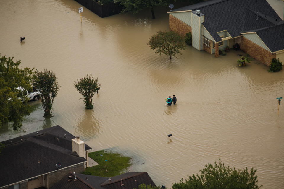 People walk through flooded neighborhoods.