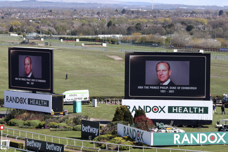 Video screens show pictures of the late Prince Philip, Duke of Edinburgh, ahead of the races on the second day of the Grand National Horse Racing meeting at Aintree racecourse, near Liverpool, England, Friday April 9, 2021. Buckingham Palace says Prince Philip, the irascible and tough-minded husband of Queen Elizabeth II, has died. He was 99. (AP Photo/Scott Heppell, Pool)