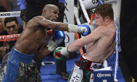 Floyd Mayweather Jr. (L) of the U.S. punches on WBC/WBA 154-pound champion Canelo Alvarez of Mexico during their title fight at the MGM Grand Garden Arena in Las Vegas, Nevada, September 14, 2013. REUTERS/Mark Hundley