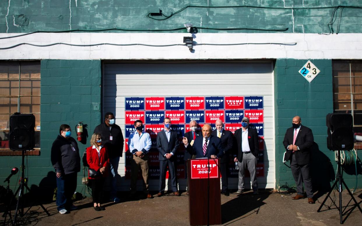 Ruddy Giuliani at a podium in a carp park - Mark Makela/Reuters