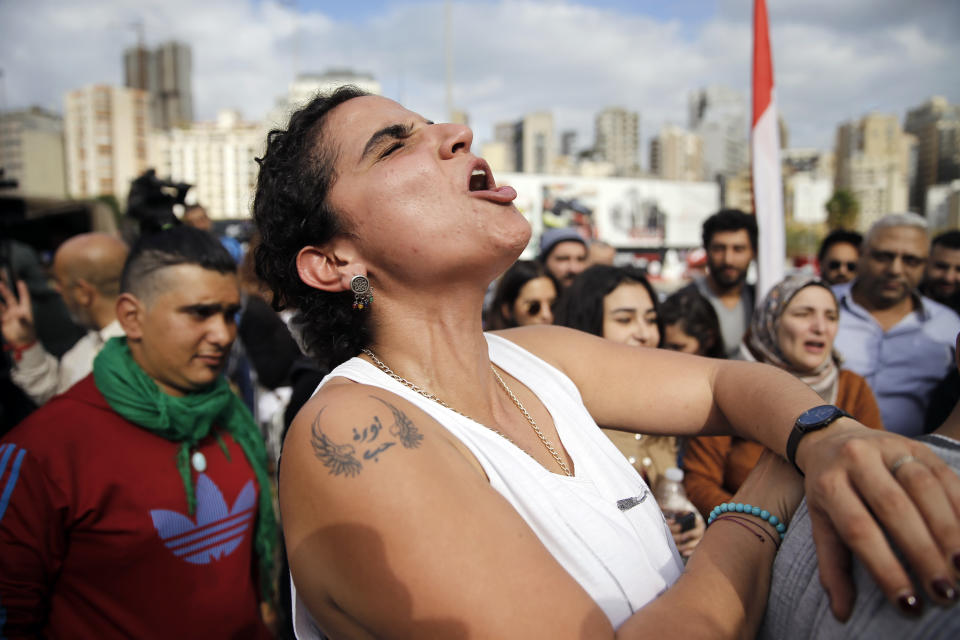 A protester with a tattoo on her arm that reads in Arabic "Love revolution" chants slogans, during ongoing protests against the Lebanese political class, in front of a Finance Ministry building in Beirut, Lebanon, Friday, Nov. 29, 2019. Protesters have been holding demonstrations since Oct. 17 demanding an end to widespread corruption and mismanagement by the political class that has ruled the country for three decades. (AP Photo/Bilal Hussein)