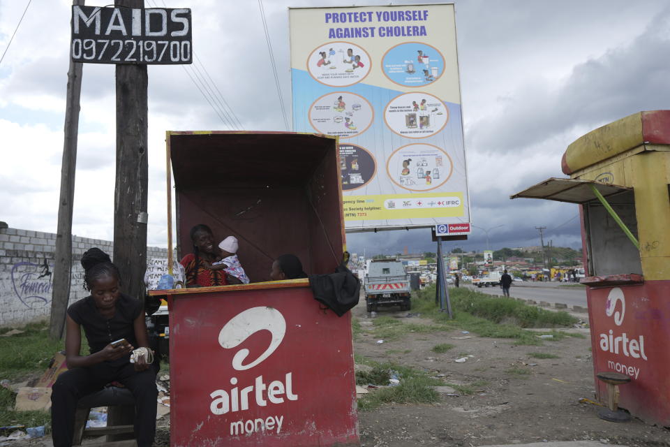 Street vendors sell phone cards under a billboard urging people to protect themselves from Cholera in Lusaka, Zambia, Sunday March, 10 2024. Extreme weather events have hit parts of Africa relentlessly in the last three years, with tropical storms, floods and drought causing crises of famine and displacement, and leaving another deadly threat in their aftermath: some of the continent's worst outbreaks of cholera. (AP Photo/Tsvangirayi Mukwazhi)