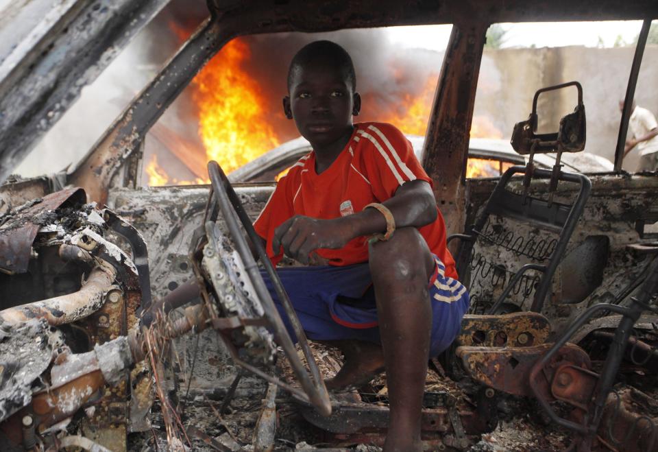 A Christian youth squats inside a burnt out car in Bangui