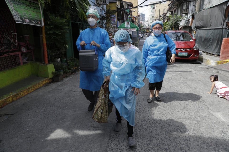 Health workers in protective suits walk to the homes of residents who are not able to go to vaccination centers in Manila, Philippines on Wednesday, May 19, 2021. Philippine President Rodrigo Duterte has eased a lockdown in the bustling capital and adjacent provinces to fight economic recession and hunger but has still barred public gatherings this month, when many Roman Catholic festivals are held. (AP Photo/Aaron Favila)