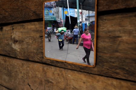 People are reflected in a mirror at La Terminal street market ahead of Sunday's presidential election in Guatemala City