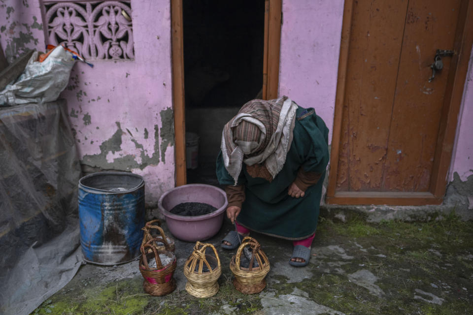 A Kashmiri woman fills a traditional firepot called Kangri with charcoal in Srinagar, Indian controlled Kashmir, Friday, Jan. 5, 2024. Kangri is an age old device for keeping warm, consisting of a decoratively woven yellow wicker case housing an earthen pot for burning charcoal. Even the modern day heating gadgets have failed to replace it, mainly due to its portability and low cost. (AP Photo/Dar Yasin)