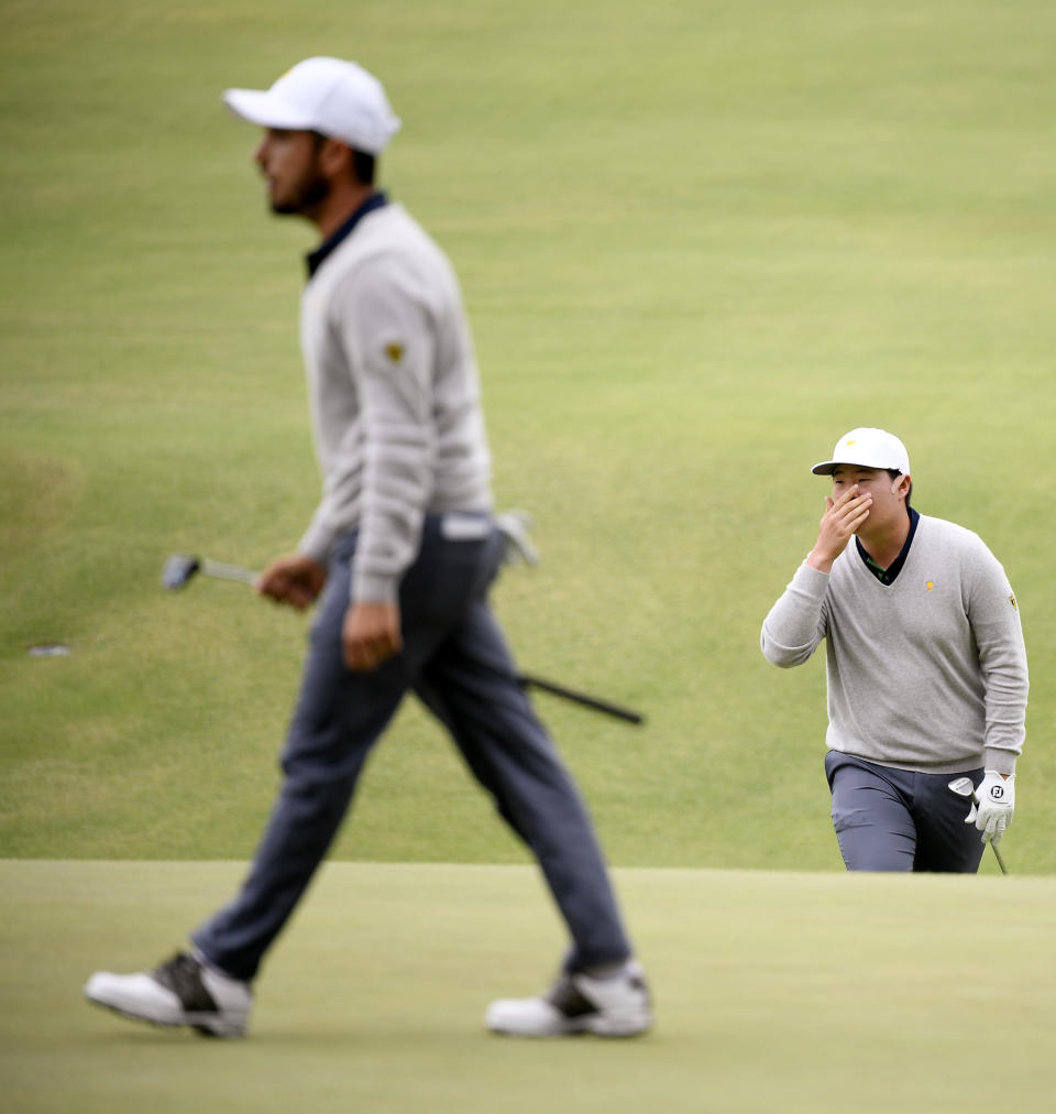 El surcoreano Sung Jae Im (derecha) se cubre el rostro en el green del 11mo hoyo al paso del mexicano Abraham Ancer durante la Copa Presidentes en Melbourne, Australia, el sábado 14 de diciembre de 2019. (AP Foto/Andy Brownbill)