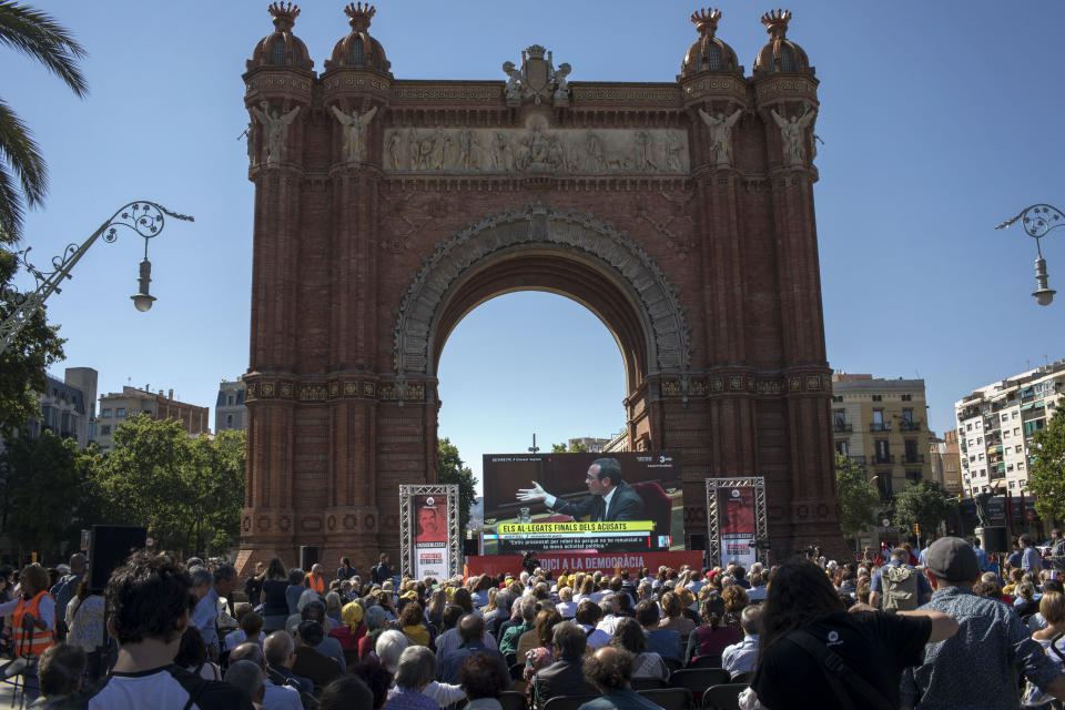 People look at a big TV screen showing the trial at Spain's Supreme Court happening Madrid on Wednesday, June 12, 2019, as they gather in downtown Barcelona, Spain. A dozen politicians and activists on trial for their failed bid in 2017 to carve out an independent Catalan republic in northeastern Spain will deliver their final statements Wednesday as four months of hearings draw to an end. (AP Photo/Emilio Morenatti)